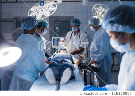 Surgical tools lying on table with nurse near and surgeons at background. 116120995