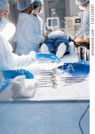Surgical tools lying on table with nurse near and surgeons at background. Surgical tools lying on table with nurse near and surgeons at background. 116120997