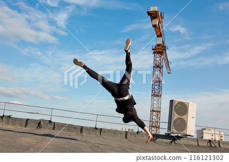 Bboy doing some acrobatic stunts on roof - Street artist breakdancing outdoors Bboy doing some acrobatic stunts on roof - Street artist breakdancing outdoors 116121302