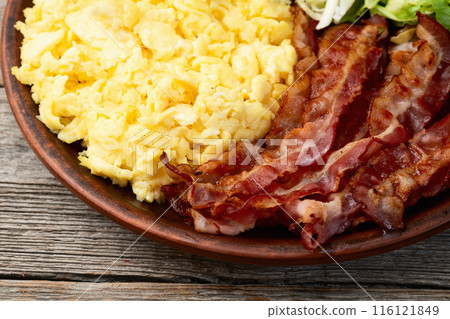 Breakfast plate . Scrambled eggs , bacon , cherry tomatoes and salad Breakfast plate . Scrambled eggs , bacon , cherry tomatoes and salad 116121849