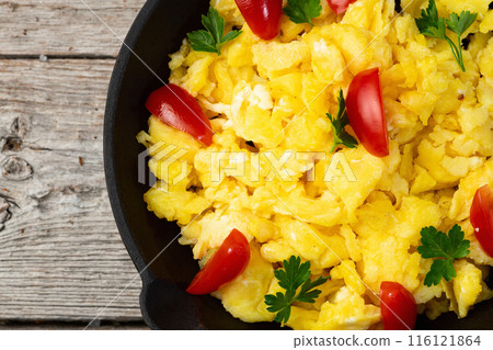 Healthy vegetarian breakfast . Scrambled eggs in pan with cherry tomatoes and parsley 116121864