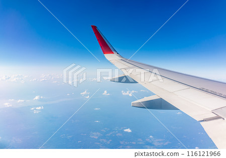 View from the airplane window at a beautiful cloudy sky and the airplane wing View from the airplane window at a beautiful cloudy sky and the airplane wing 116121966