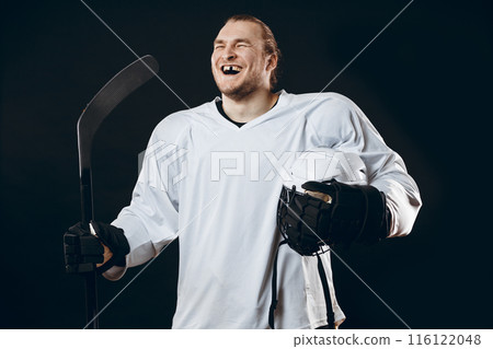 Handsome hockey player. Smiling at camera isolated on black background. 116122048