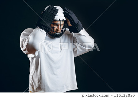 Handsome hockey player. Smiling at camera isolated on black background. 116122050