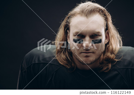 Determined American football player posing with painted face and chewing gum 116122149
