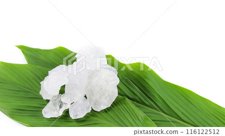 White crystal clear alum cube on green leaf isolated on white background. 116122512