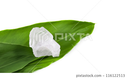 White crystal clear alum cube on green leaf isolated on white background. White crystal clear alum cube on green leaf isolated on white background. 116122513