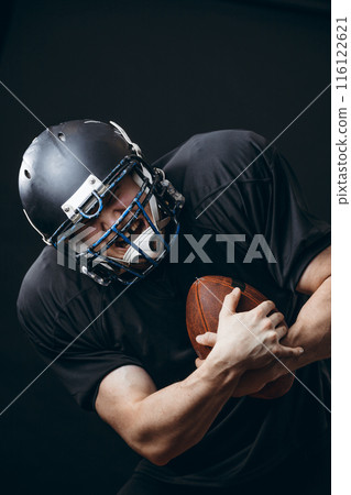 American football sportsman player in action isolated over black studio wall 116122621
