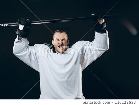 Handsome hockey player. Smiling at camera isolated on black background. 116122658