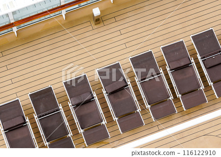 A fragment of the plank deck of a luxury cruise ship with brown sun loungers in a row, no people 116122910