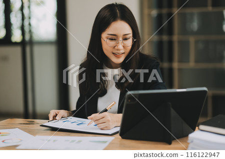 Pretty young Asian businesswoman sitting in office using laptop computer. 116122947