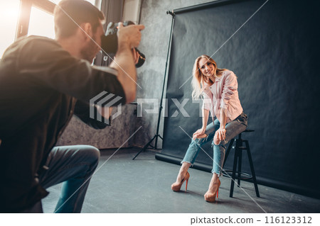 smiling positive model in fashion clothes sitting on the chair smiling positive model in fashion clothes sitting on the chair 116123312