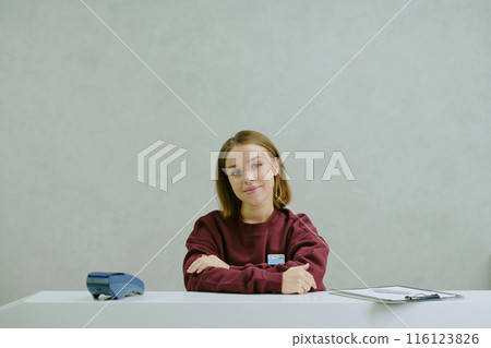 Young professional manager sitting at snow white work desk, she folding her arms and smiling lightly Young professional manager sitting at snow white work desk, she folding her arms and smiling lightly 116123826