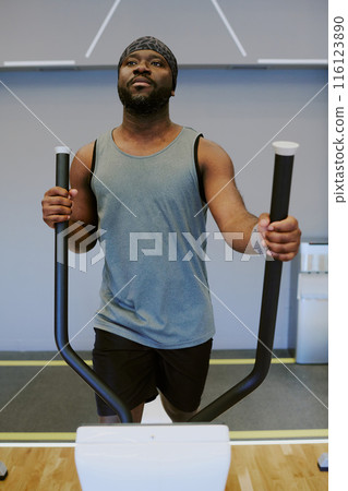 Calm African American sportsman dressed in gray tank top and sport shorts warming up before workout, he immersed in his own thoughts 116123890