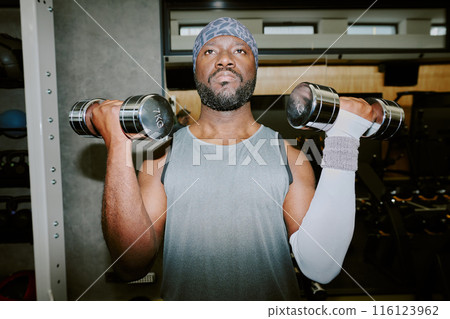 African American man lifting heavy dumbbells, he focused on exercise technique African American man lifting heavy dumbbells, he focused on exercise technique 116123962