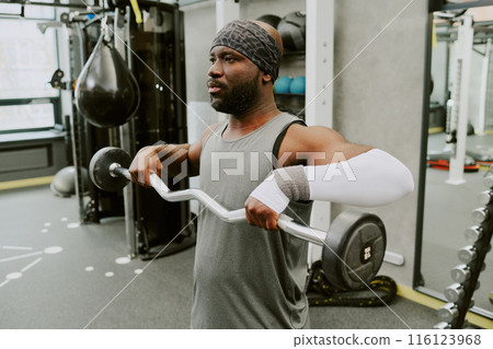 Young African American man doing high pull to make his shoulder muscle stronger Young African American man doing high pull to make his shoulder muscle stronger 116123968
