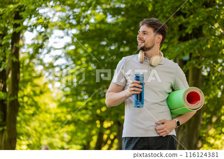 Athletic fitness sport runner man with yoga mat drinking water from bottle after training exercise Athletic fitness sport runner man with yoga mat drinking water from bottle after training exercise 116124381
