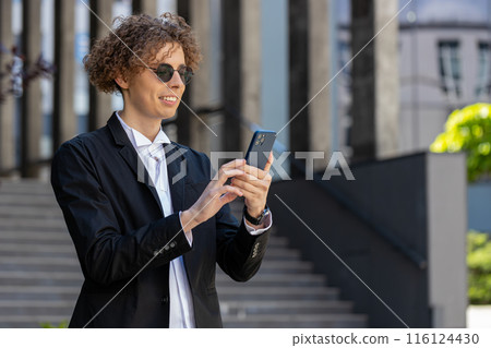 Happy businessman using smartphone typing text answering e-mail messages online mobile app outdoors 116124430