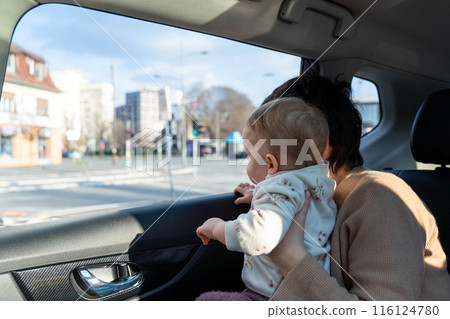 A baby in his mothers arms without a seat belt in a car A baby in his mothers arms without a seat belt in a car 116124780