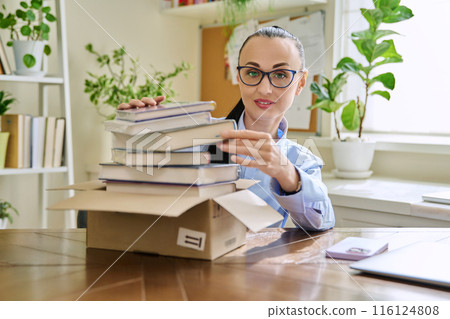 Woman with new books unpacked from cardboard box 116124808