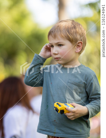 A young boy is holding a toy car and talking on a cell phone A young boy is holding a toy car and talking on a cell phone 116124941
