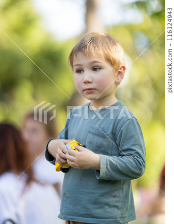 A young boy is holding a toy car in his hand A young boy is holding a toy car in his hand 116124943
