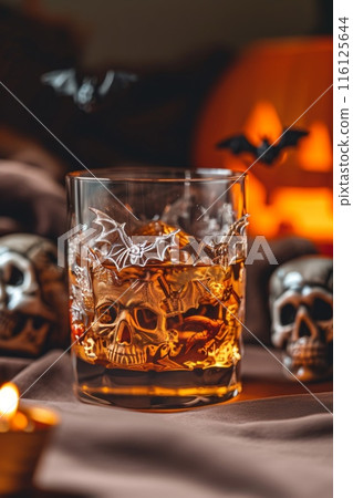 Halloween themed drink with bat decoration in a crystal glass surrounded by skulls and pumpkins. 116125644