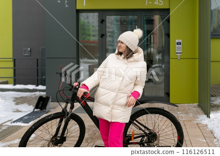 Woman Standing Next to Bike in Front of Building 116126511