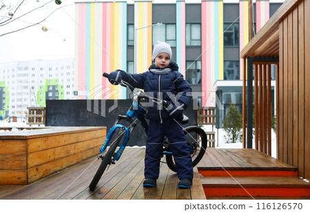 European boy dressed in winter clothes took his bike outside 116126570