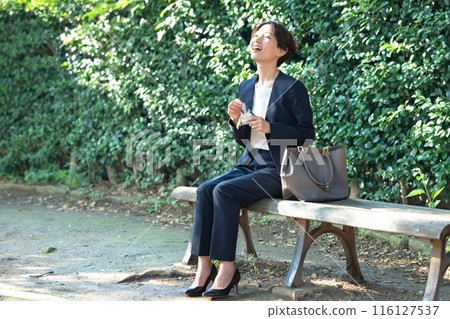 A woman sitting on a bench eating rice balls A woman sitting on a bench eating rice balls 116127537