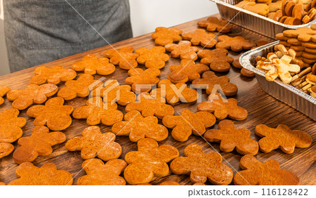 Making gingerbread man cookie sandwiches filled with eggnog buttercream, arrayed on a rustic wooden table, ideal for heartfelt Christmas gifting. Making gingerbread man cookie sandwiches filled with eggnog buttercream, arrayed on a rustic wooden table, ideal for heartfelt Christmas gifting. 116128422