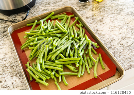 Watch as fresh green beans are beautifully roasted to perfection on a baking sheet with a silicone mat, adding a burst of flavor to your meal. 116128430