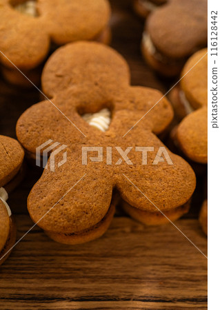 Making gingerbread man cookie sandwiches filled with eggnog buttercream, arrayed on a rustic wooden table, ideal for heartfelt Christmas gifting. 116128442
