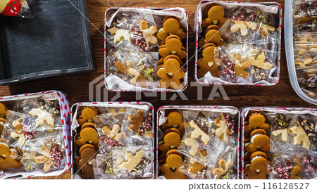 Flat lay. Lovingly homemade gingerbread and sugar cookies, half-dipped in rich chocolate, nestled in decorative Christmas tin boxes perfect for seasonal gifting. 116128527