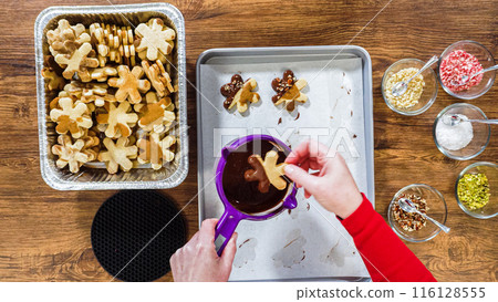 Flat lay. Creating snowflake-shaped cutout sugar cookies, dipped in chocolate, and adorned with different toppings. Flat lay. Creating snowflake-shaped cutout sugar cookies, dipped in chocolate, and adorned with different toppings. 116128555