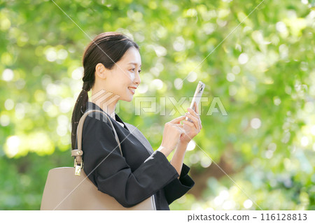 Profile of a woman in a suit holding a smartphone Profile of a woman in a suit holding a smartphone 116128813