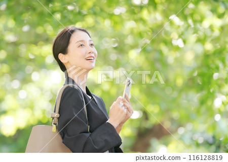 Profile of a woman in a suit holding a smartphone Profile of a woman in a suit holding a smartphone 116128819