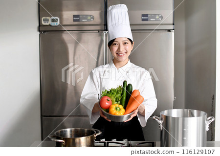 年輕的亞洲女廚師用大量蔬菜 年輕的亞洲女廚師用大量蔬菜 116129107