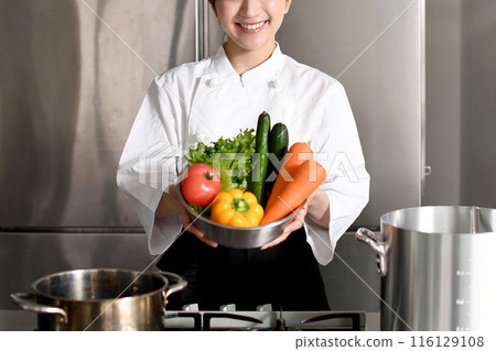 Young Asian female chef holding lots of vegetables 116129108