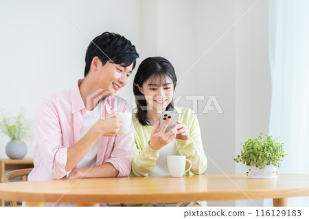 年輕夫婦在家看智慧型手機 年輕夫婦在家看智慧型手機 116129183