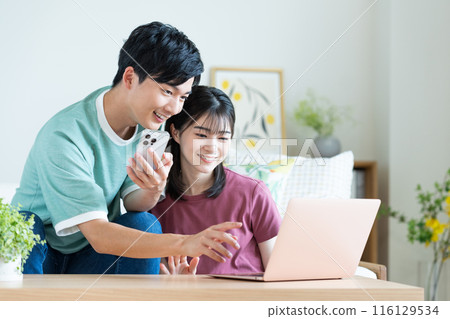 Young couple looking at a computer in the living room Young couple looking at a computer in the living room 116129534
