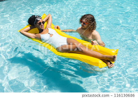 A diverse couple enjoys sunny day in pool 116130686