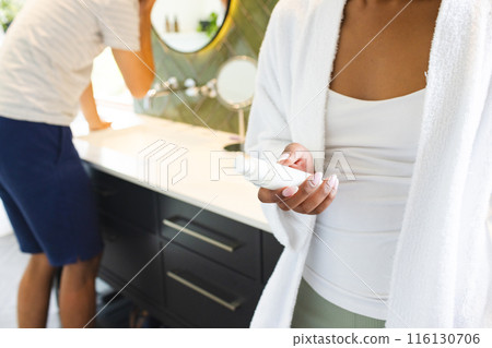 A diverse couple is in a bright bathroom, doing their morning skincare routine 116130706