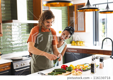A diverse couple is preparing food together in modern kitchen A diverse couple is preparing food together in modern kitchen 116130718