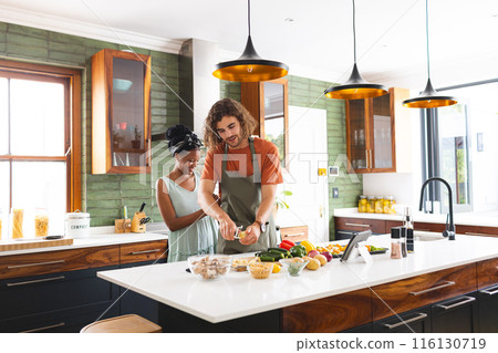 A diverse couple is preparing meal together in a modern kitchen 116130719