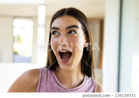 A young Caucasian brunette woman expresses excitement at home 116130731