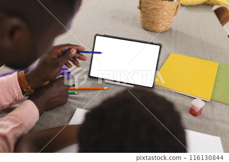 Father and son, both African American, focusing on tablet with copy space and doing homework Father and son, both African American, focusing on tablet with copy space and doing homework 116130844