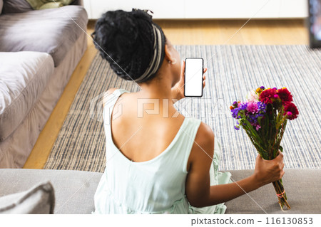 African American woman holding flowers, showing phone on a video call date with copy space African American woman holding flowers, showing phone on a video call date with copy space 116130853