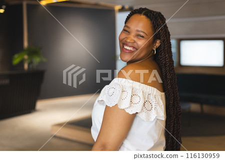 A young biracial woman is smiling in a modern business office with copy space 116130959