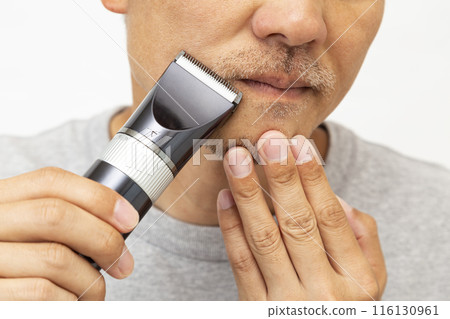 A man shaving his beard on a white background 116130961